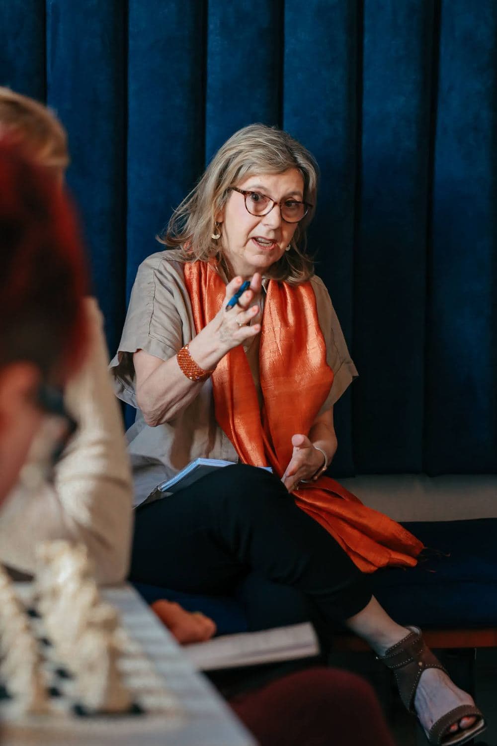 A facilitator with an orange scarf speaking during a small-group justice conversation